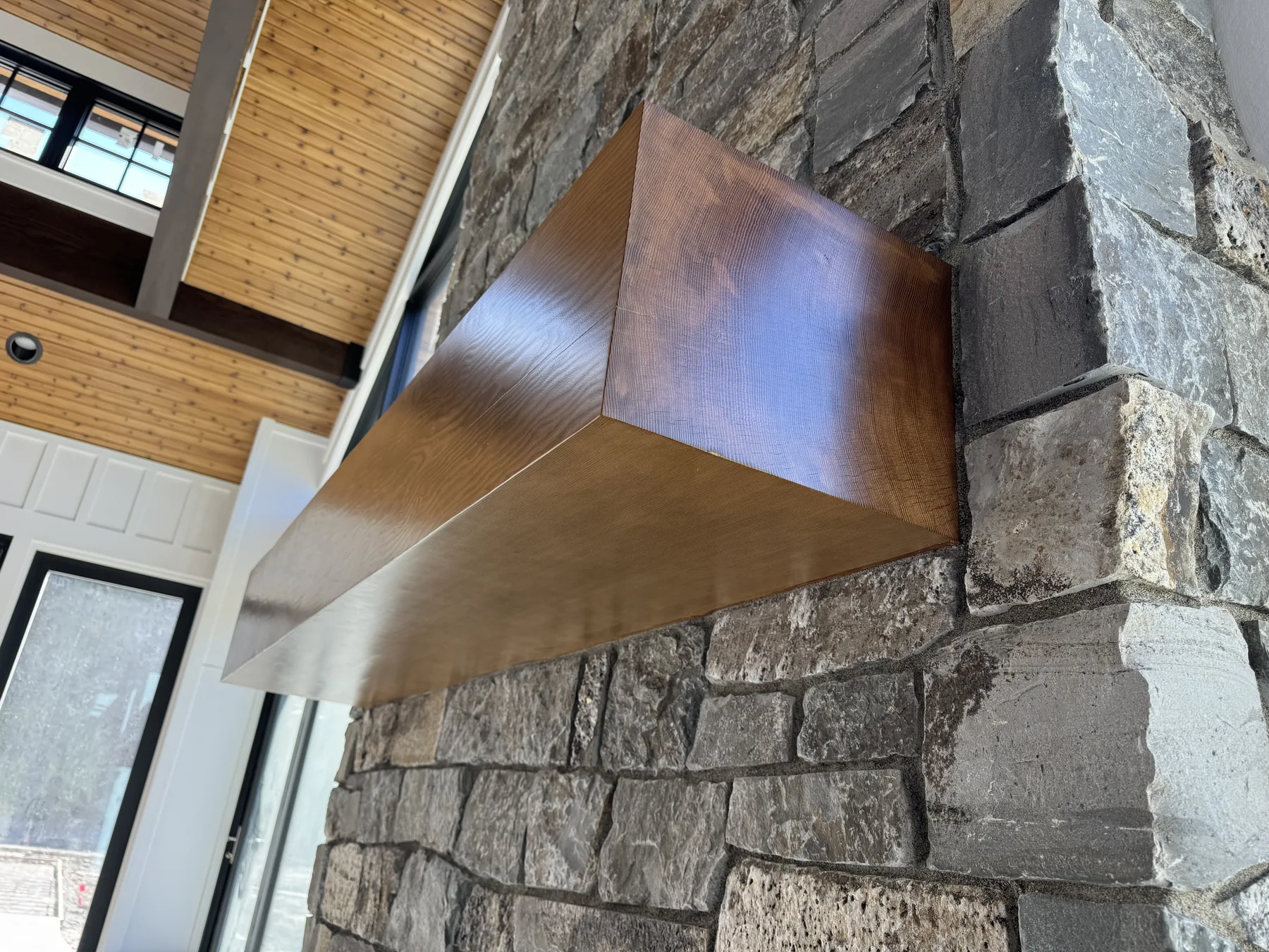Solid Douglas Fir mantel beam cantilevered from a stacked stone fireplace surround